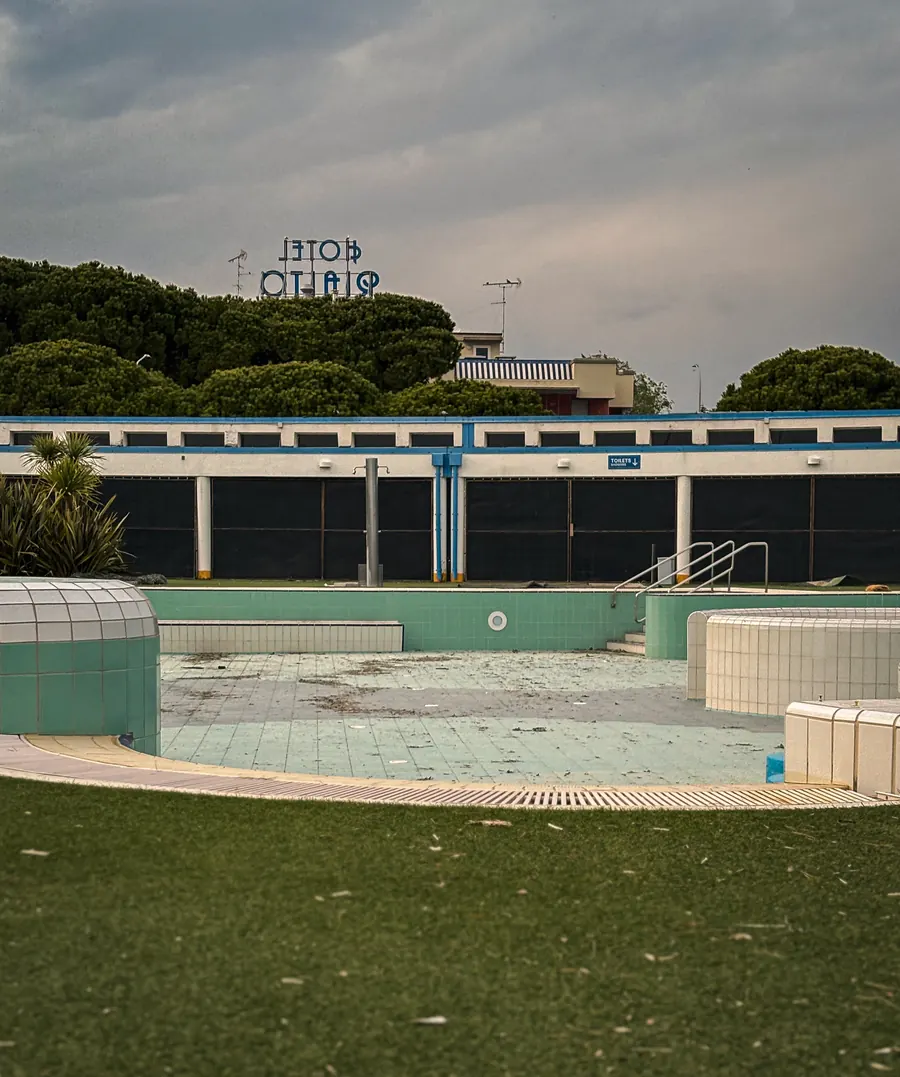 Empty outdoor pool off season, Hotel Rialto sign above the trees