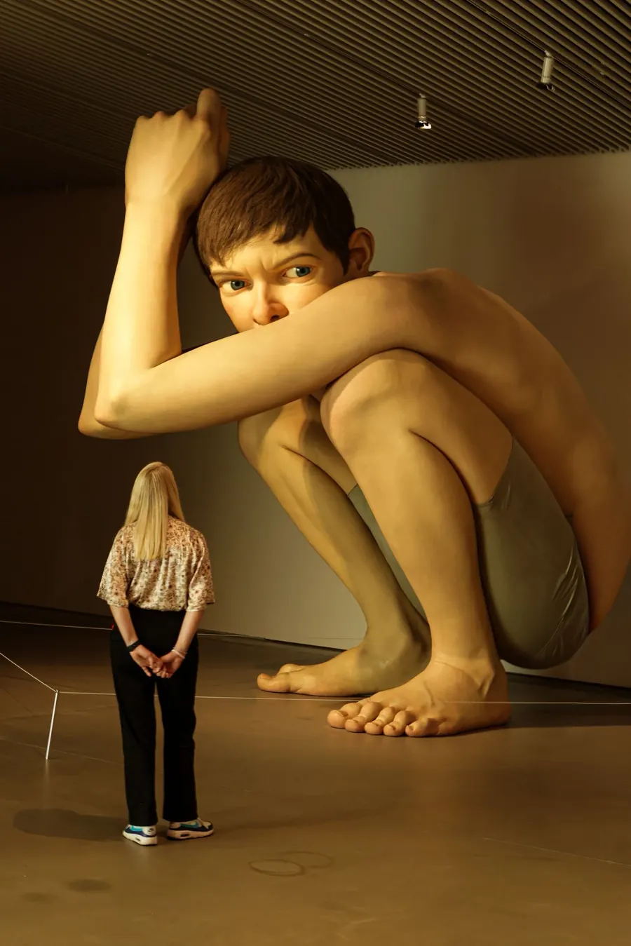 Woman standing before a giant sculpture of a crouching boy
