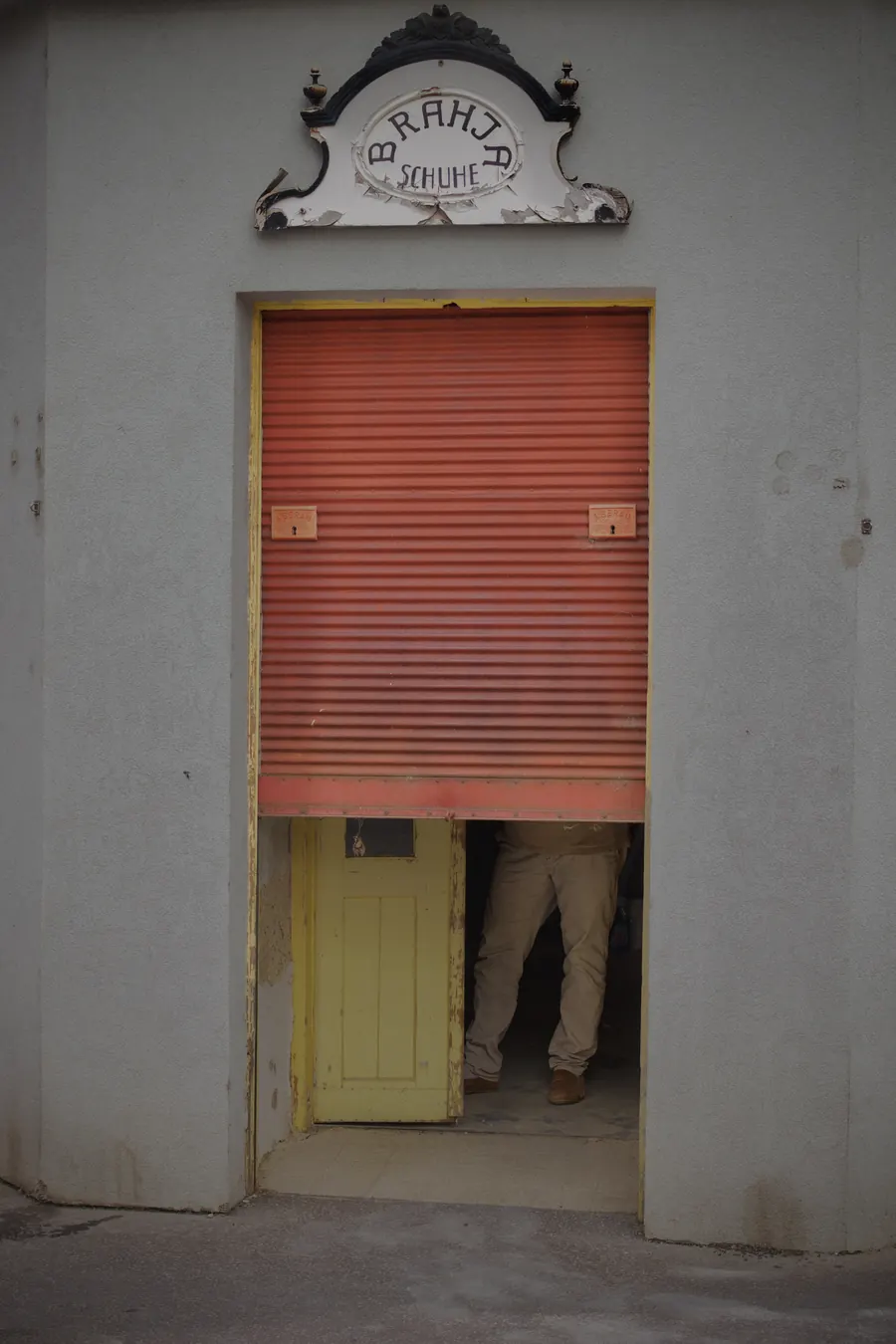 Half-lowered red shutter beneath an ornate shop sign, Vienna