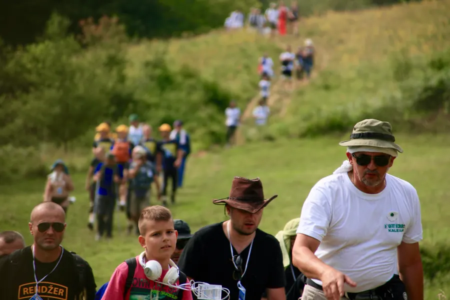 Column of marchers climbing a green hillside