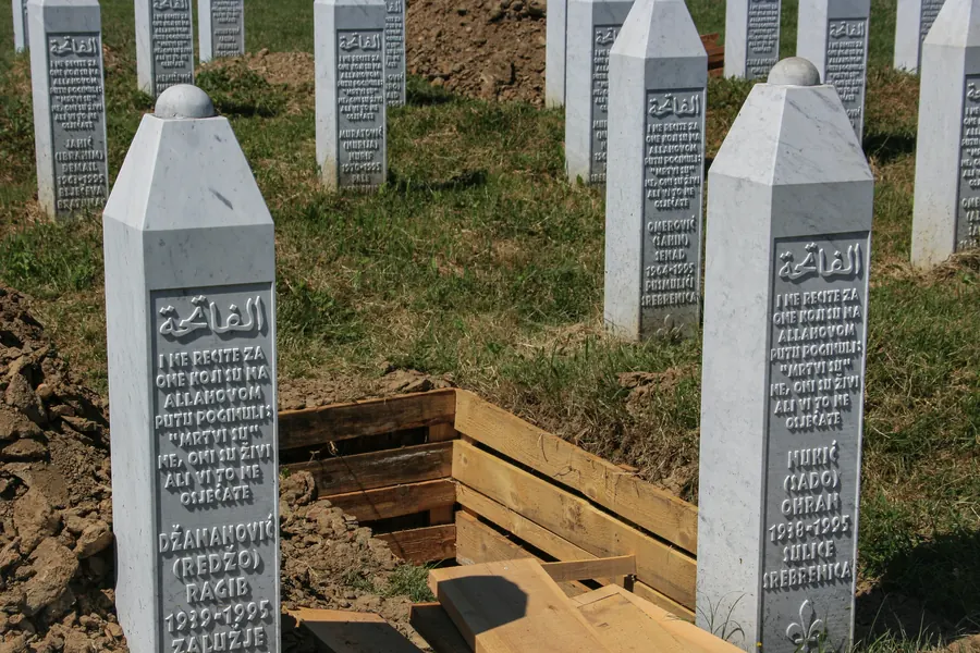 White gravestones and an open grave at the Potočari memorial cemetery