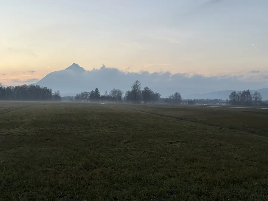 Meadow at dusk, mountain rising above low mist