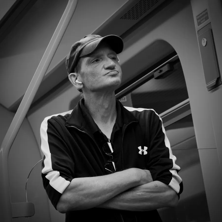Man with cap and crossed arms in a train