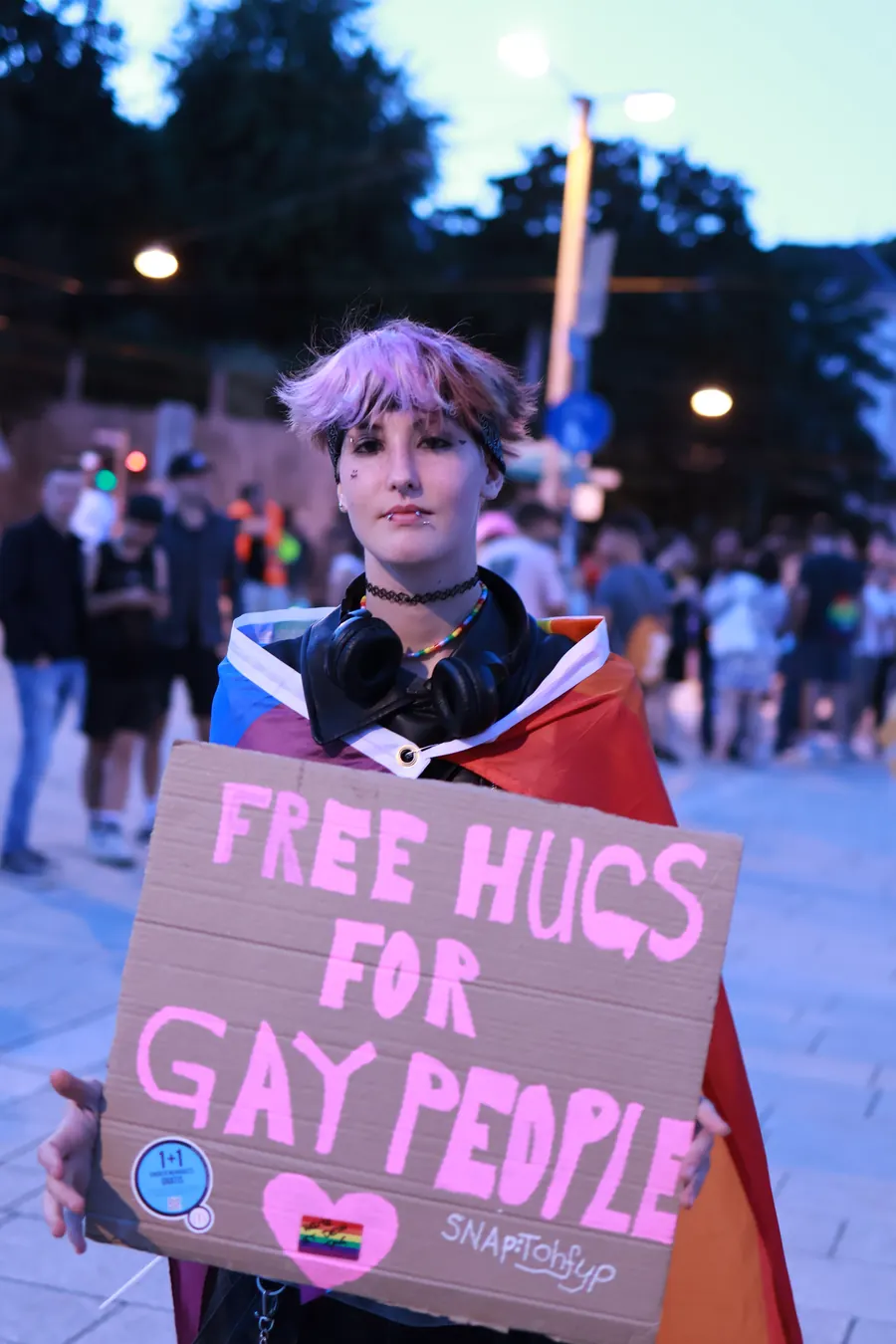 Young person holding a Free Hugs sign at Pride