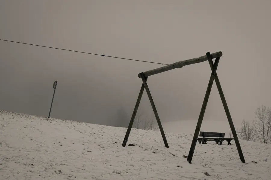 Swing frame on a snowy slope in fog