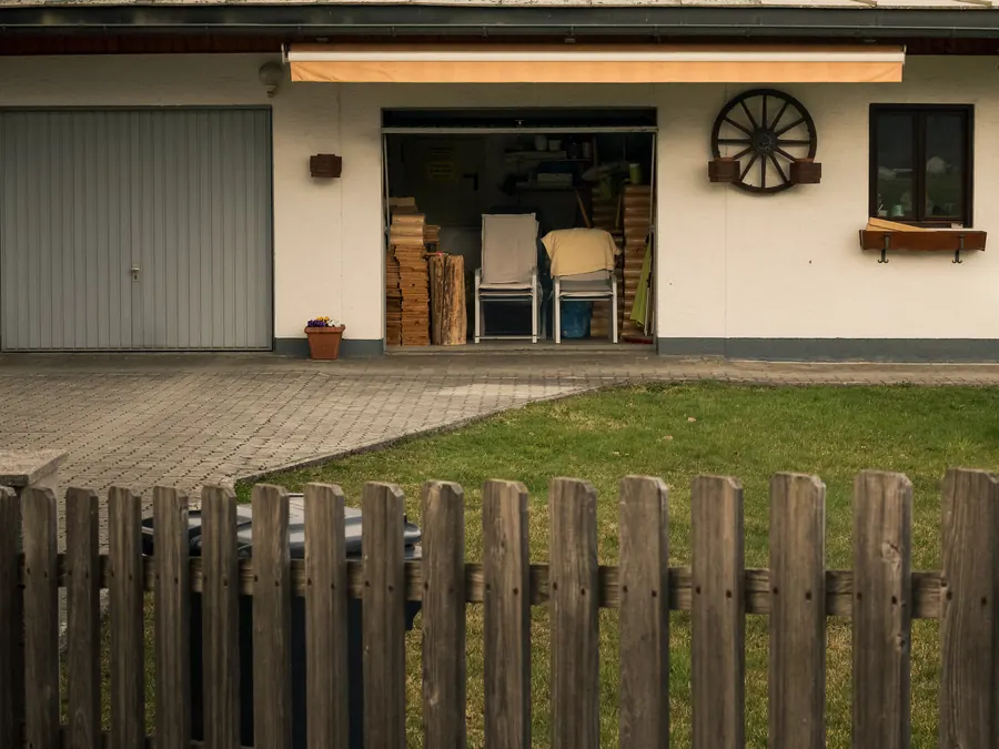 Open garage with stacked chairs behind a wooden fence