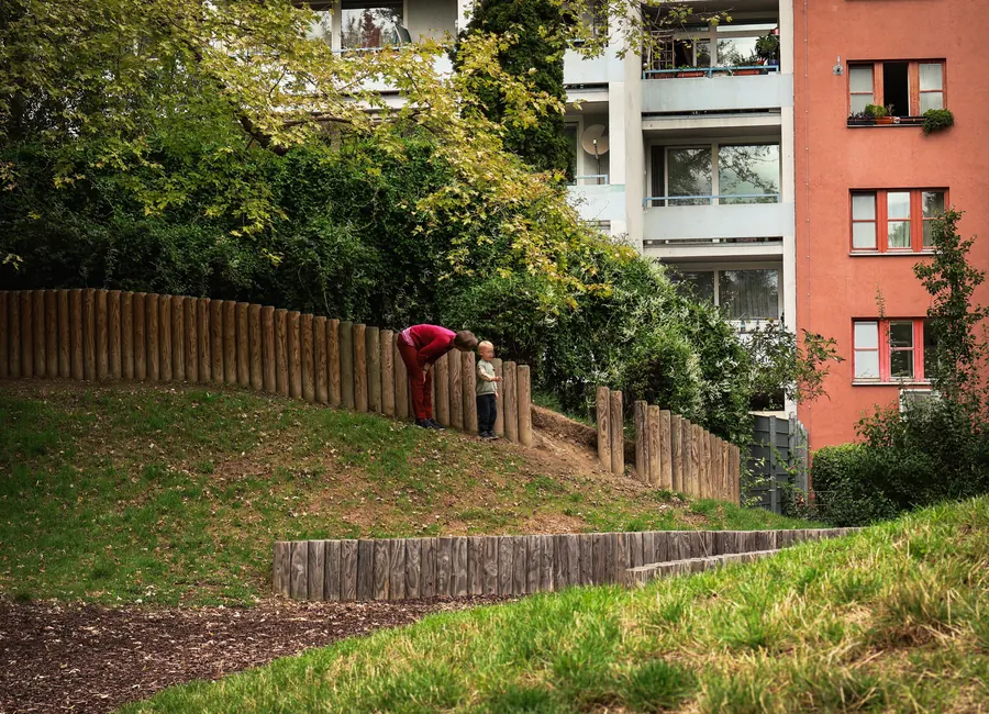 Red slide on a grassy slope beneath apartment buildings