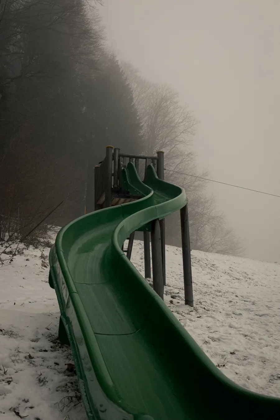 Green slide descending into fog on a snowy slope