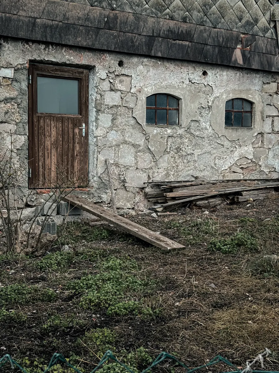 Old stone farmhouse with a wooden door and stacked planks
