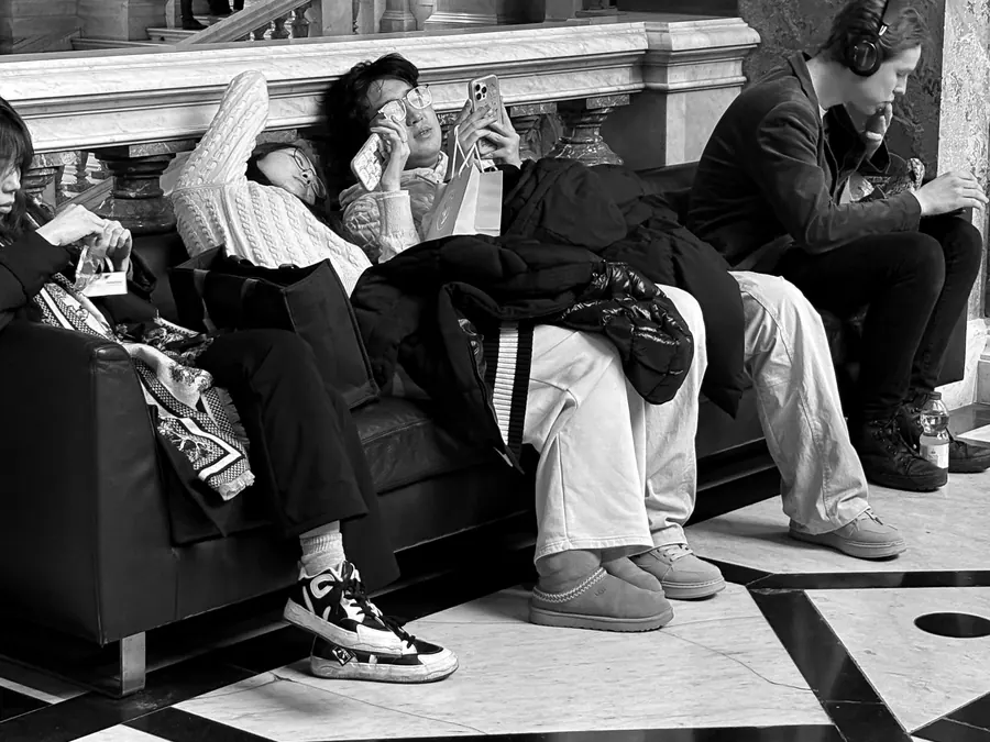 Tired visitors slumped on a leather sofa in a museum hall