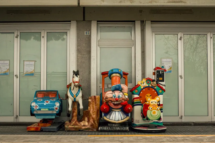 Coin-operated kiddie rides lined up in front of closed shop windows