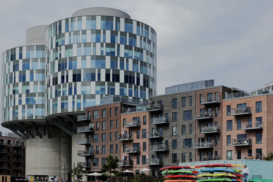 Round glass silo tower above brick buildings, colourful kayaks below