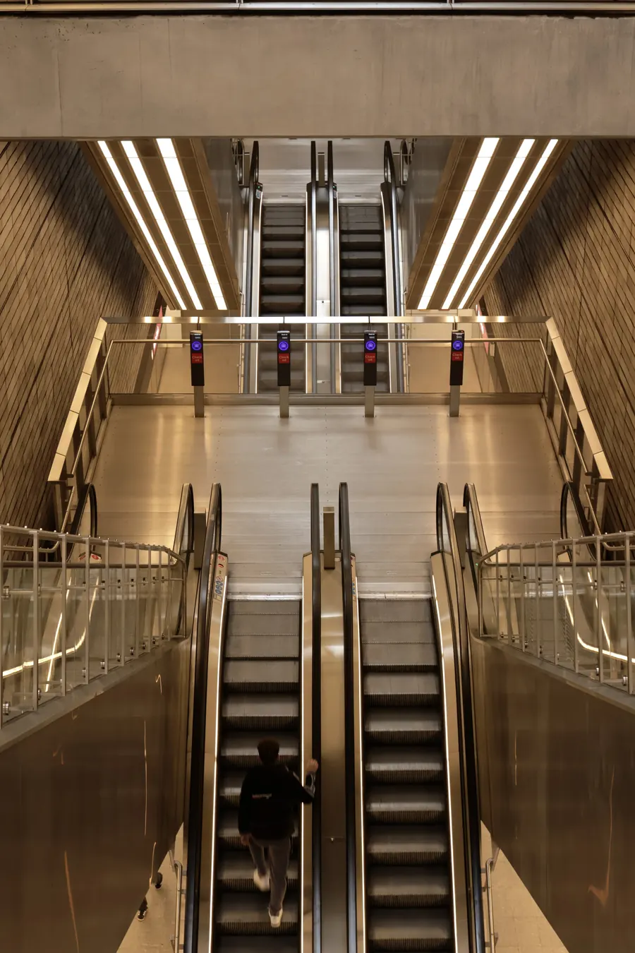 Symmetrical metro escalators lit in warm gold